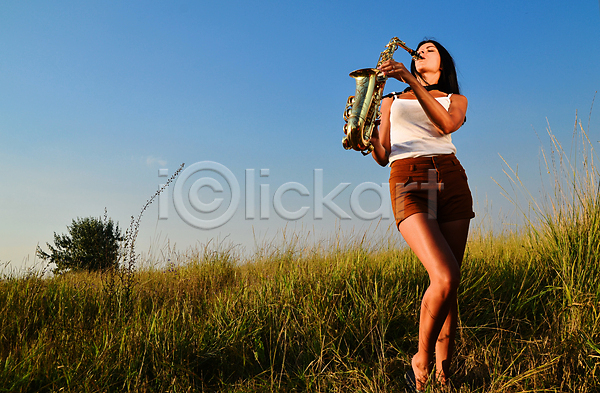 성인 성인여자한명만 여자 한명 JPG 앞모습 포토 해외이미지 들기 불기 색소폰 야외 연주 음악 전신 주간 하늘 해외202004