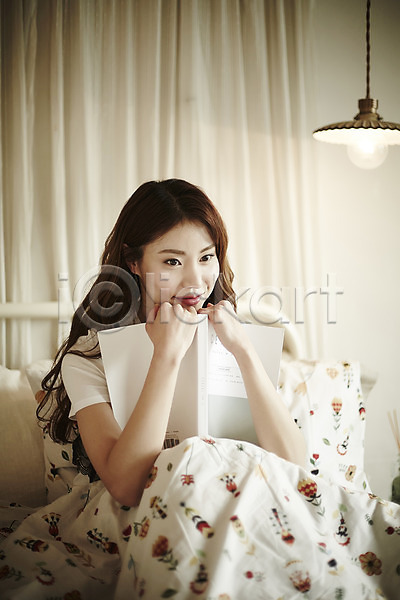 20대 성인 성인여자한명만 여자 한국인 한명 JPG 앞모습 포토 기댐 들기 상반신 실내 앉기 웃음 응시 이불 조명 책 침대