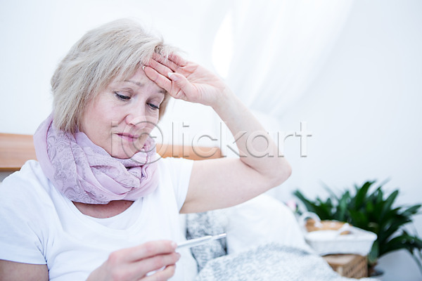 고통 50대 백인 여자 중년 중년여자한명만 한명 JPG 아웃포커스 앞모습 포토 감기(질병) 들기 상반신 실내 앉기 온도계 응시 체온계 침대