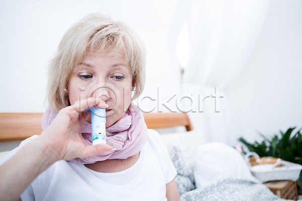 50대 백인 여자 중년 중년여자한명만 한명 JPG 아웃포커스 앞모습 포토 비염 상반신 실내 앉기 약 응시 침대 코세정기