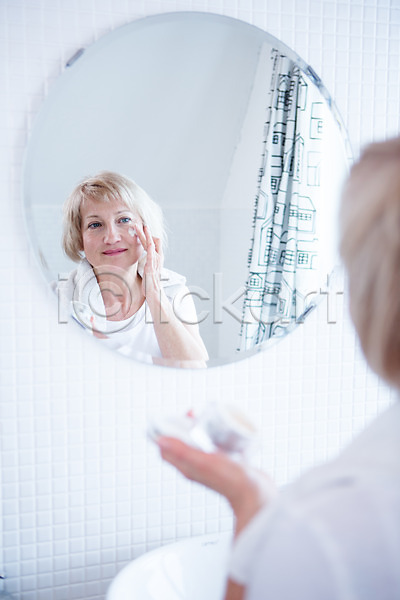 50대 백인 여자 중년 중년여자한명만 한명 JPG 아웃포커스 앞모습 포토 거울 로션 바르기 상반신 서기 세면대 실내 응시 의료성형뷰티 화장실