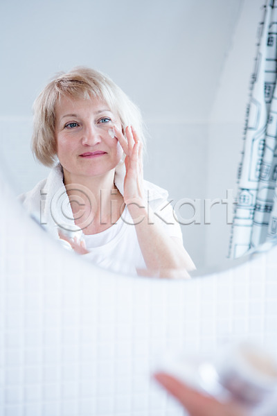 50대 백인 여자 중년 중년여자한명만 한명 JPG 포토 거울 로션 바르기 상반신 서기 세면대 실내 웃음 응시 의료성형뷰티 화장실