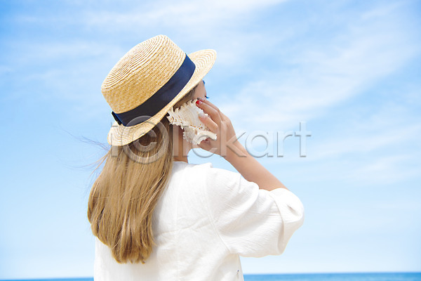 여유 평화 행복 휴식 20대 성인 성인여자한명만 여자 한명 JPG 뒷모습 아웃포커스 포토 고둥 들기 바다 상반신 서기 야외 여름(계절) 여름풍경 일상 주간 풍경(경치) 하늘 해변 휴가
