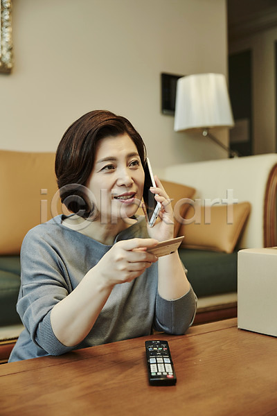 50대 여자 중년 중년여자한명만 한국인 한명 JPG 아웃포커스 앞모습 포토 거실 들기 리모컨 미소(표정) 상반신 소파 스마트폰 신용카드 실내 앉기 응시 주문 중년라이프 택배 택배상자 통화