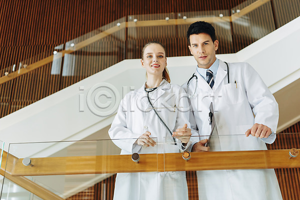 20대 남자 두명 서양인 성인 성인만 여자 JPG 로우앵글 아웃포커스 앞모습 포토 계단 들기 미소(표정) 상반신 서기 서류판 실내 의사 의사가운 청진기