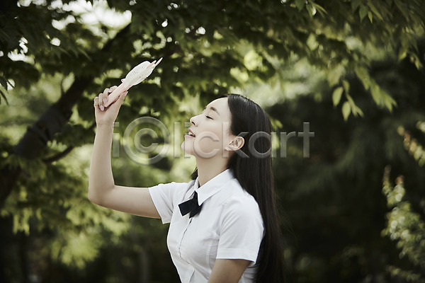 20대 성인 성인여자한명만 여자 한국인 한명 JPG 아웃포커스 옆모습 포토 공원 교복 나무 눈감음 들기 상반신 서기 손풍기 야외 주간 학생