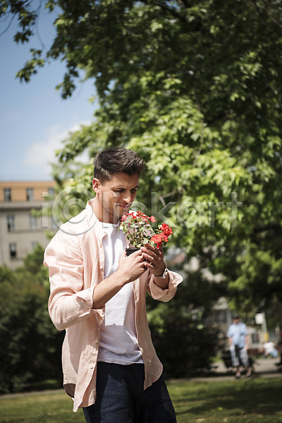 20대 남자 서양인 성인 성인남자한명만 한명 JPG 아웃포커스 앞모습 포토 꽃 나무 들기 미소(표정) 상반신 서기 야외 유럽 잔디 주간 체코 프라하 화분