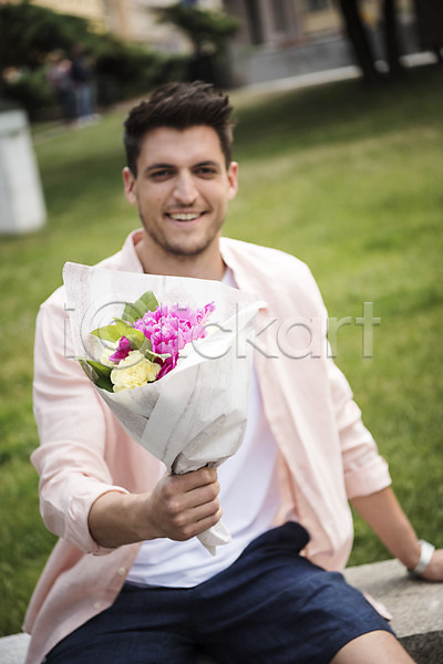 20대 남자 서양인 성인 성인남자한명만 한명 JPG 아웃포커스 앞모습 포토 꽃다발 들기 미소(표정) 상반신 앉기 야외 유럽 잔디 주간 체코 프라하