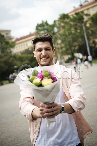 20대 남자 서양인 성인 성인남자한명만 한명 JPG 아웃포커스 앞모습 포토 꽃다발 나무 들기 미소(표정) 상반신 서기 야외 유럽 주간 체코 프라하