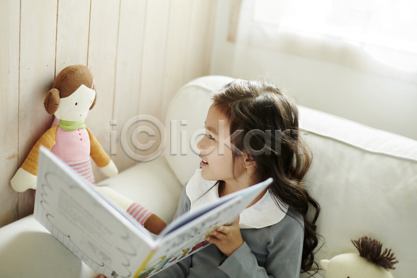 즐거움 소녀한명만 어린이 여자 한국인 한명 JPG 앞모습 포토 동화책(책) 미소(표정) 상반신 소파 실내 앉기 어린이라이프 인형 인형놀이