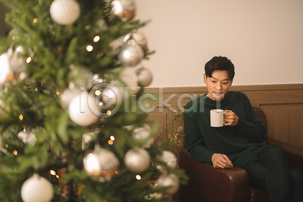 휴식 20대 남자 성인 성인남자한명만 한국인 한명 JPG 아웃포커스 앞모습 포토 거실 들기 상반신 소파 실내 앉기 응시 커피 크리스마스 크리스마스트리