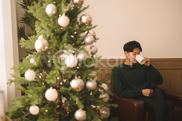 휴식 20대 남자 성인 성인남자한명만 한국인 한명 JPG 아웃포커스 앞모습 포토 거실 마시기 상반신 소파 실내 앉기 커피 크리스마스 크리스마스트리