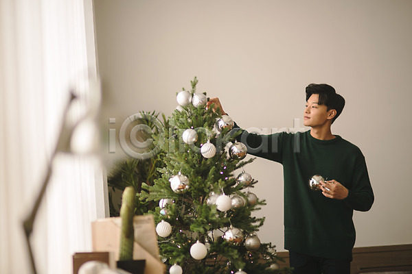 휴식 20대 남자 성인 성인남자한명만 한국인 한명 JPG 아웃포커스 앞모습 포토 거실 들기 미소(표정) 상반신 서기 실내 응시 크리스마스 크리스마스장식 크리스마스트리