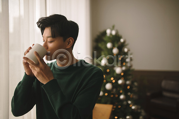 휴식 20대 남자 성인 성인남자한명만 한국인 한명 JPG 아웃포커스 앞모습 포토 거실 들기 마시기 상반신 실내 앉기 응시 커피 커피잔 크리스마스 크리스마스트리