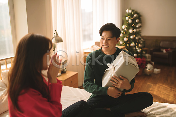 다정 20대 30대 남자 두명 성인 성인만 여자 한국인 JPG 아웃포커스 앞모습 옆모습 포토 들기 미소(표정) 상반신 선물 실내 앉기 침대 커플 크리스마스 크리스마스트리