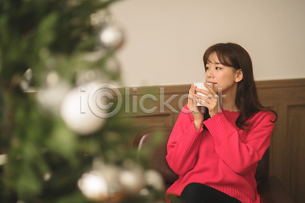 휴식 30대 성인 성인여자한명만 여자 한국인 한명 JPG 아웃포커스 앞모습 포토 거실 들기 머그컵 미소(표정) 상반신 실내 앉기 응시 크리스마스 크리스마스트리