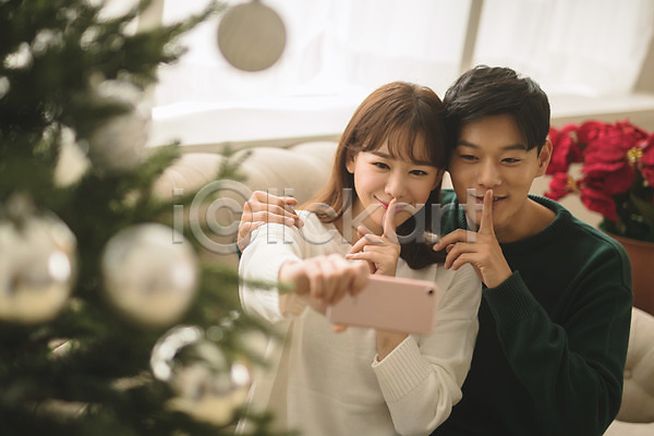 다정 20대 30대 남자 두명 성인 성인만 여자 한국인 JPG 아웃포커스 앞모습 포토 거실 들기 미소(표정) 상반신 셀프카메라 쉿 스마트폰 실내 앉기 커플 크리스마스 크리스마스트리