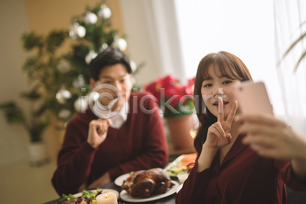 다정 20대 30대 남자 두명 성인 성인만 여자 한국인 JPG 아웃포커스 앞모습 포토 들기 미소(표정) 브이 상반신 셀프카메라 스마트폰 식탁 실내 앉기 음식 커플 크리스마스 크리스마스트리 포크