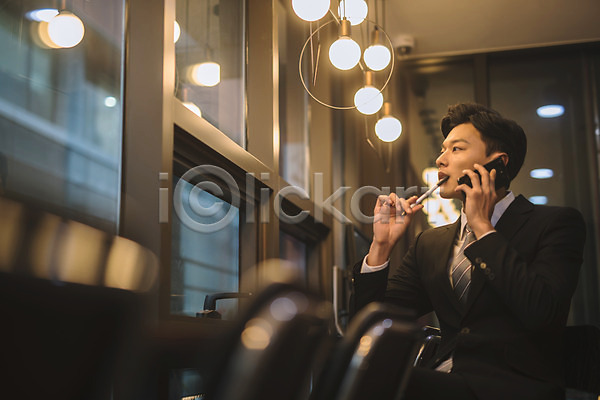 20대 남자 성인 성인남자한명만 한국인 한명 JPG 아웃포커스 옆모습 포토 비즈니스맨 상반신 스마트폰 실내 안식처 앉기 조명 직장인 카페 통화