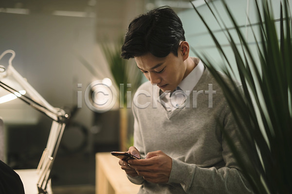 20대 남자 성인 성인남자한명만 한국인 한명 JPG 아웃포커스 앞모습 포토 들기 미소(표정) 비즈니스맨 사무실 상반신 서기 스마트폰 식물 실내 응시 직장인