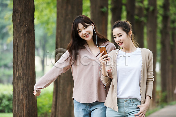 우정 20대 30대 두명 성인 성인여자만 여자 한국인 JPG 앞모습 포토 걷기 공원 나무 들기 미소(표정) 상반신 스마트폰 싱글라이프 야외 우먼라이프 음악감상 이어폰 주간 친구