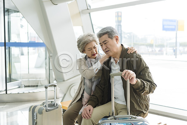고통 60대 남자 노년 노인만 두명 여자 한국인 JPG 앞모습 포토 공항 노부부 상반신 실내 앉기 어깨에손 어깨주무르기 여행 울상 의자 인천국제공항 주간 캐리어 힘듦