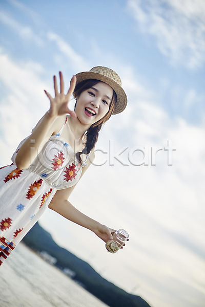 20대 사람 성인여자한명만 여자 한국인 한명 JPG 앞모습 포토 구름(자연) 들기 맑음 미소(표정) 비치웨어 상반신 서기 손짓 야외 여름(계절) 영흥도 유리병 주간 챙모자 하늘 해변