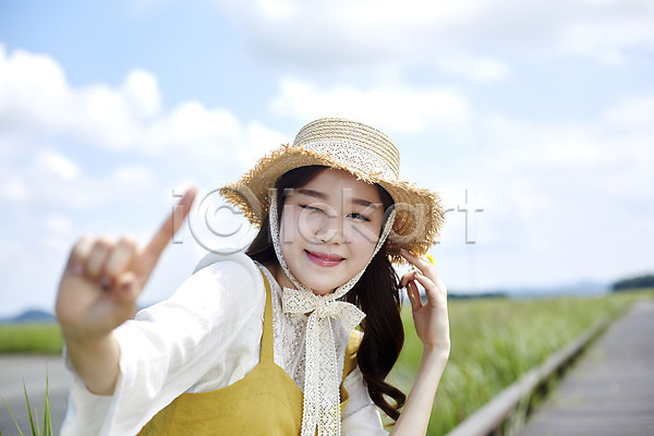 즐거움 20대 사람 성인여자한명만 여자 한국인 한명 JPG 앞모습 포토 갈대습지 구름(자연) 다리(건축물) 맑음 미소(표정) 상반신 서기 손가락 손짓 야외 우음도 윙크 주간 챙모자 하늘