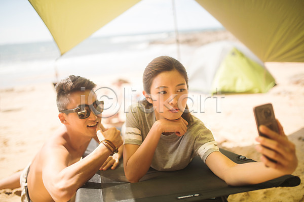 즐거움 20대 30대 남자 두명 사람 성인만 여자 한국인 JPG 아웃포커스 앞모습 포토 모래사장 미소(표정) 상반신 셀프카메라 스마트폰 야외 엎드리기 여름(계절) 주간 커플 태안 텐트 해변