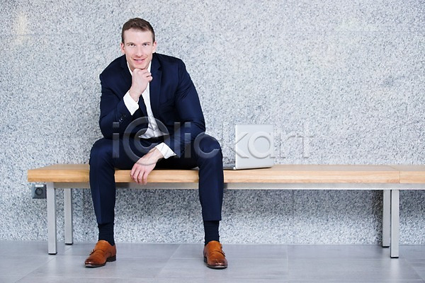 30대 남자 사람 서양인 성인 성인남자한명만 한명 JPG 앞모습 포토 미소(표정) 벤치 비즈니스 비즈니스맨 사무실 실내 앉기 응시 의자 전신 정장 턱괴기