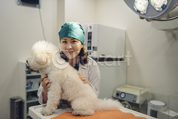 20대 사람 성인 성인여자한명만 여자 한국인 한명 JPG 앞모습 포토 개 동물병원 미소(표정) 반려 반려견 반려동물 비숑프리제 상반신 수술복 수의사 실내 응시 의료기계 조명 진료 진찰가방 펫팸족 한마리