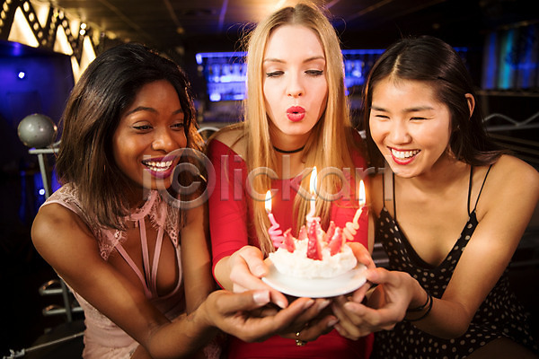 즐거움 축하 20대 30대 동양인 사람 서양인 성인 성인여자만 세명 여자 흑인 JPG 앞모습 포토 미소(표정) 바람불기 불기 상반신 생일 생일축하 실내 조명 촛불 친구 케이크 클럽 파티