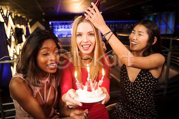 즐거움 축하 20대 30대 동양인 사람 서양인 성인 성인여자만 세명 여자 흑인 JPG 앞모습 옆모습 포토 고깔(모자) 들기 미소(표정) 상반신 생일 생일축하 소파 실내 앉기 응시 촛불 친구 케이크 클럽 파티