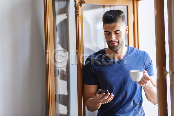 20대 남자 사람 서양인 성인 성인남자한명만 한명 JPG 앞모습 포토 들기 상반신 실내 응시 창가 창문 커피잔 핸드폰