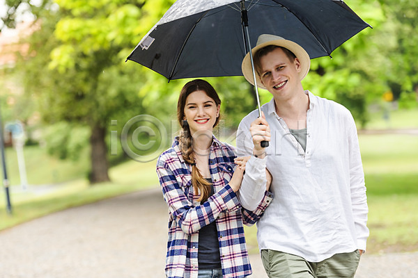 산책 20대 남자 두명 사람 서양인 성인 여자 JPG 앞모습 포토 공원 데이트 들기 미소(표정) 비(날씨) 상반신 우산 응시 잔디 주머니손 챙모자 커플 팔짱