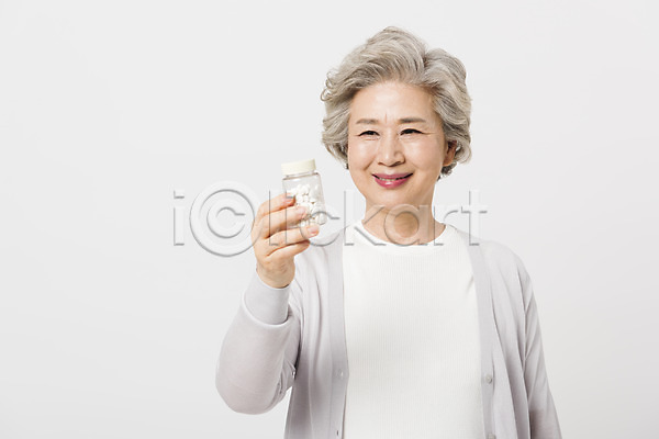 60대 노년 노인여자한명만 사람 여자 한국인 한명 JPG 앞모습 포토 건강 건강관리 들기 미소(표정) 상반신 서기 스튜디오촬영 실내 실버라이프 알약 약병 응시 할머니