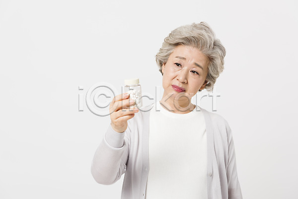 의심 60대 노년 노인여자한명만 사람 여자 한국인 한명 JPG 앞모습 포토 건강 건강관리 들기 상반신 서기 스튜디오촬영 실내 실버라이프 알약 약병 응시 할머니