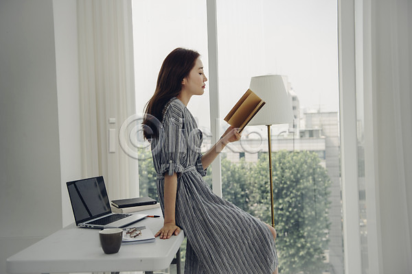 20대 사람 성인 성인여자한명만 여자 한국인 한명 JPG 옆모습 포토 거실 걸터앉기 노트북 상반신 실내 싱글 싱글라이프 우먼라이프 읽기 주간 창가 창문 책 책상 프리랜서
