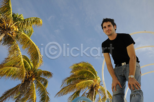 시원함 20대 남자 사람 소년 한명 JPG 포토 해외이미지 나무 내추럴 노려봄 모델 서기 손바닥 야외 여름(계절) 응시 코코넛 파란색 하늘 해외202004 히스패닉