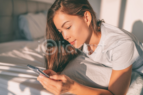 여유 휴식 성인 성인여자한명만 여자 한명 JPG 포토 해외이미지 들기 라이프스타일 모바일 미소(표정) 상반신 엎드리기 일상 침대 핸드폰 햇빛