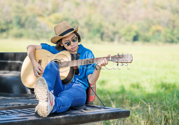 동양인 성인 성인여자한명만 여자 한명 JPG 아웃포커스 앞모습 포토 해외이미지 기타 기타리스트 선글라스 앉기 야외 여름(계절) 연주 전신 주간 짧은머리 초원(자연)