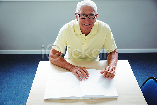 남자 노년 노인남자한명만 한명 JPG 앞모습 포토 해외이미지 독서 라이프스타일 미소(표정) 상반신 손짚기 시각장애인 실내 안경낌 앉기 점자 점자책 책상