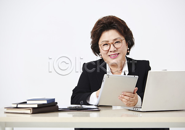 50대 사람 여자 중년 중년여자한명만 한국인 한명 JPG 앞모습 포토 노트북 다이어리 미소(표정) 상반신 스튜디오촬영 실내 안경낌 앉기 엄마 워킹맘 응시 정장 중년라이프 직장인 책상 태블릿 흰배경