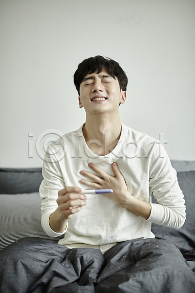 기쁨 20대 남자 사람 성인 성인남자한명만 한국인 한명 JPG 앞모습 포토 눈감음 미소(표정) 부부라이프 상반신 실내 안도 앉기 임신 임신테스트기 침대