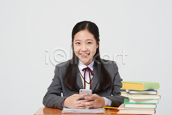 10대 십대여자한명만 여자 중학생 청소년 한국인 한명 JPG 앞모습 포토 교복 딴짓 미소(표정) 상반신 수업 스마트폰 스튜디오촬영 실내 십대라이프스타일 앉기 여중생 여학생 의자 책 책더미 책상 흰배경