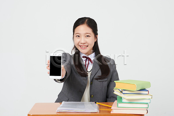 10대 십대여자한명만 여자 중학생 청소년 한국인 한명 JPG 앞모습 포토 교복 미소(표정) 보여주기 상반신 스마트폰 스튜디오촬영 실내 십대라이프스타일 앉기 여중생 여학생 연필 의자 책 책더미 책상 흰배경