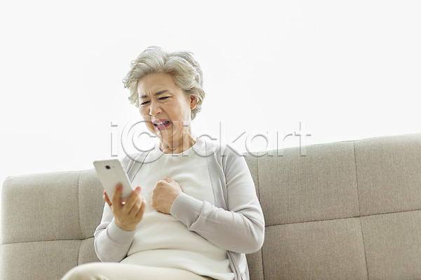 답답함 60대 노년 노인여자한명만 사람 여자 한국인 한명 JPG 로우앵글 앞모습 포토 가슴 두드리기 상반신 소파 스마트폰 스튜디오촬영 실내 실버라이프 앉기 응시 일상 찡그림 할머니