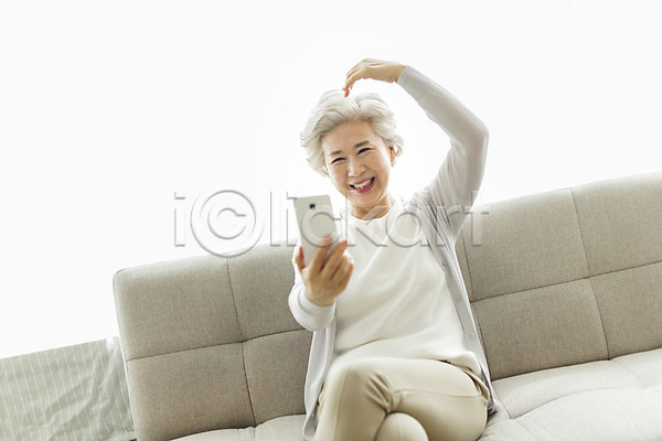 60대 노년 노인여자한명만 사람 여자 한국인 한명 JPG 앞모습 포토 다리꼬기 들기 미소(표정) 상반신 소파 손하트 스마트폰 스튜디오촬영 실내 실버라이프 앉기 영상통화 응시 일상 할머니