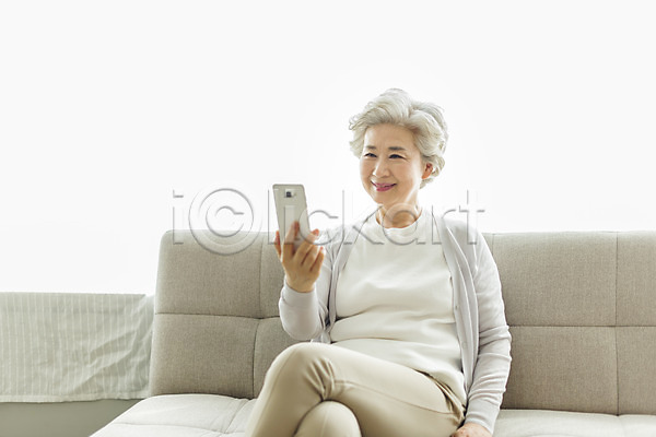 60대 노년 노인여자한명만 사람 여자 한국인 한명 JPG 앞모습 포토 다리꼬기 들기 미소(표정) 상반신 소파 스마트폰 스튜디오촬영 실내 실버라이프 앉기 영상통화 응시 일상 할머니