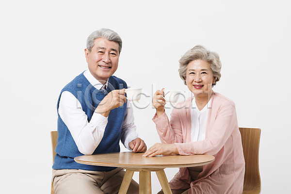 휴식 60대 70대 남자 노년 노인만 두명 사람 여자 한국인 JPG 앞모습 포토 노부부 들기 마시기 미소(표정) 상반신 스튜디오촬영 실내 실버라이프 앉기 응시 의자 일상 책상 커피 커피잔 할머니 할아버지 흰배경